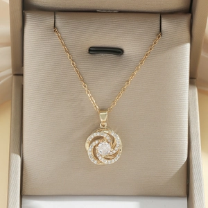 Nahaufnahme eines goldenen Wirbelanhängers mit zentralem Kristall in einer Geschenkbox