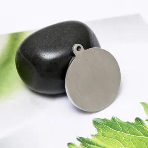 Macro shot of circular stainless steel pendant with raw brushed finish and top hanging hole