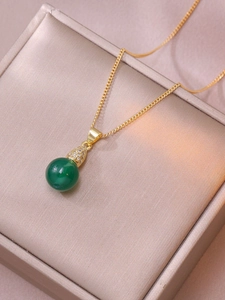 Elegante collar dorado con colgante de piedra verde redonda y detalles de circón