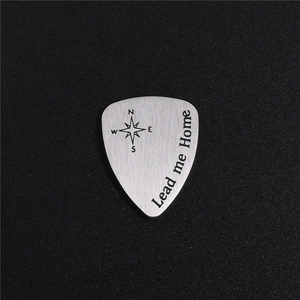 Makroaufnahme von Edelstahl Gitarren-Plektrum mit Kompass und Lead me home Text