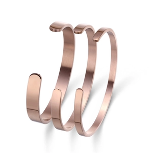 Detailed macro view of three rose gold C-shaped titanium steel bracelets with brushed finish
