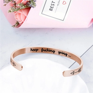 Détail du bracelet jonc en or rose avec gravure Keep Fucking Going et flèches