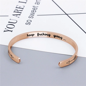 Gros plan du bracelet jonc en acier rose doré avec gravure Keep Fucking Going