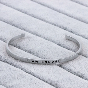 Minimalist silver stainless steel cuff bracelet with I AM ENOUGH engraving on velvet