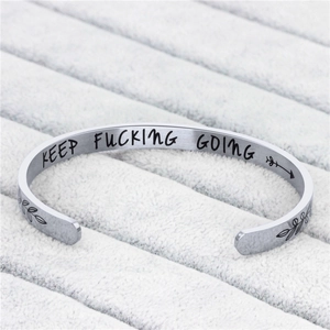 Dettaglio macro del bracciale in acciaio argento con incisione Keep Fucking Going
