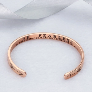Detail eines roségoldenen Armreifs mit motivierender Be Fearless Gravur und Pfeil