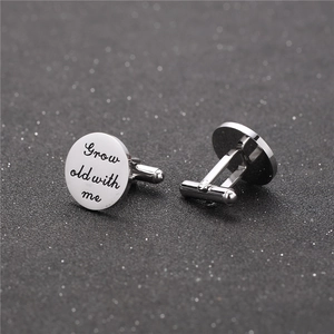 Close-up of polished silver cufflinks engraved with Grow old with me text for shirts