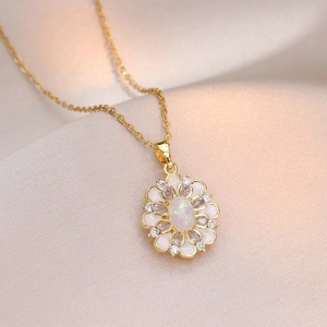 Collier fleur doré élégant avec centre opale et émail blanc posé sur soie
