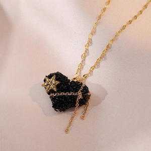 Collier élégant en titane doré avec cœur en cristal noir et détail de pompon étoile