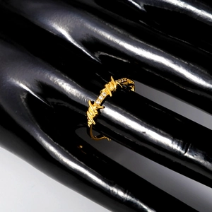 Anello a filo di spine dorato con cristalli scintillanti su mano da esposizione