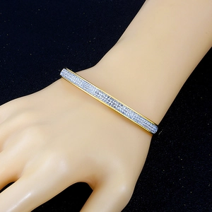 Bracelet jonc en acier doré orné de cristaux scintillants sur le poignet d'un modèle