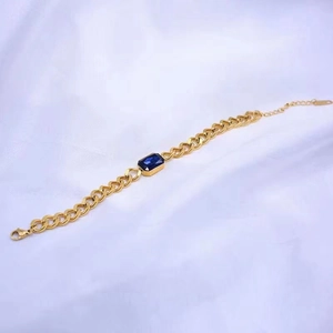 Detail eines vergoldeten Gliederketten-Armbands mit einem rechteckigen blauen Kristall