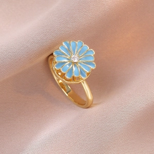 Rotating sunflower ring with blue enamel petals and sparkling zircon on golden band