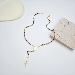 Gold stainless steel rosary necklace with purple beads and a cross pendant on a stone