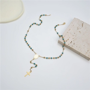 Vintage gold cross necklace with turquoise beads and saint medal on white background