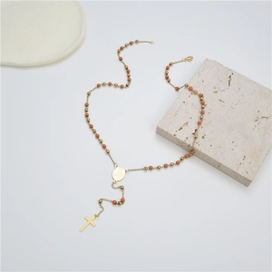 Detailed close-up of orange bead rosary necklace with gold cross and lobster clasp