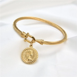 Dettaglio del bracciale a cavo dorato con ciondolo moneta Elizabeth II e chiusura a gancio
