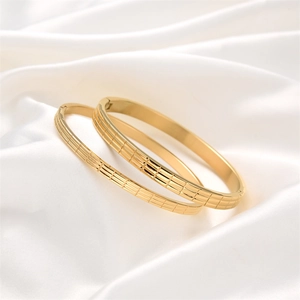 Set of two gold stainless steel bangles with elegant lattice pattern and side buckle