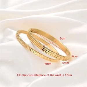 Detail view of gold stainless steel bangle set with grid pattern and polished finish