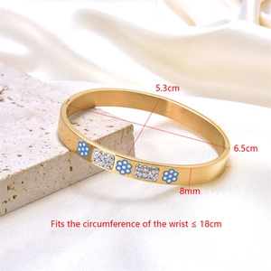 Detailed macro view of 8mm gold plated stainless steel bangle with blue enamel flowers