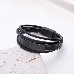 Mehrlagiges Herren-Lederarmband in Schwarz mit mattem Magnetverschluss auf hellem Stein