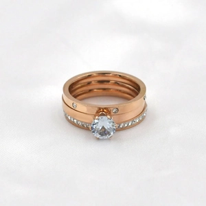 Set di tre anelli in oro rosa con pietra centrale a sei griffe e fasce in pavé di cristalli