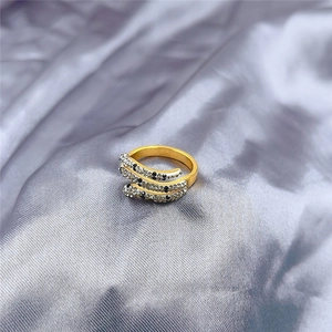 Détail d'une bague serpent dorée multicouche sertie de cristaux sur fond de soie grise