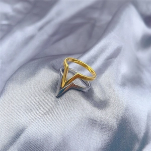 Macro view of gold and silver V-shaped titanium steel rings on silk background