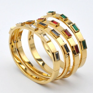 Detalle de brazaletes de acero dorado con piedras preciosas rectangulares de colores