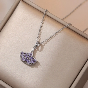 Pendentif feuille de ginkgo argentée avec zircons violets dans un écrin à bijoux