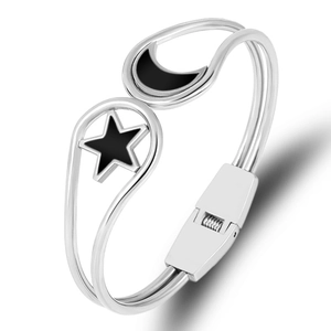 Detail view of silver stainless steel open bangle featuring black star and moon charms