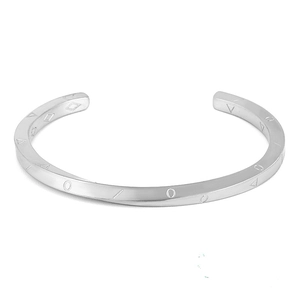 Dettaglio macro del bracciale rigido in acciaio argento con texture geometrica