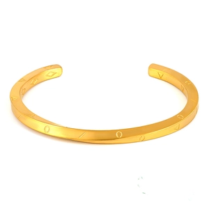 Dettaglio del bracciale rigido a spirale in acciaio dorato con simboli incisi