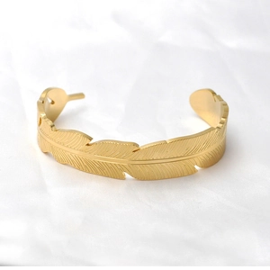 Dettaglio del bracciale rigido dorato in acciaio inossidabile con trama a piuma