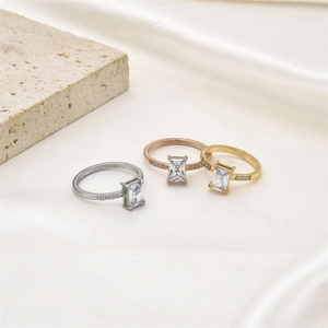 Tres anillos con cristal rectangular en plata, oro y oro rosa sobre un fondo de seda blanca