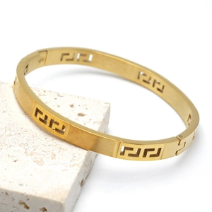Close-up of gold titanium steel bangle showing Greek key cutout and side clasp