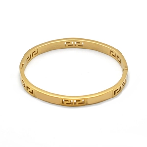 Close-up of golden titanium steel bangle with intricate Greek Key pattern cutouts