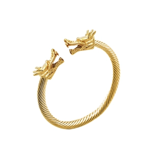 Detalle de cabezas de dragón talladas y textura de cable trenzado en el brazalete dorado