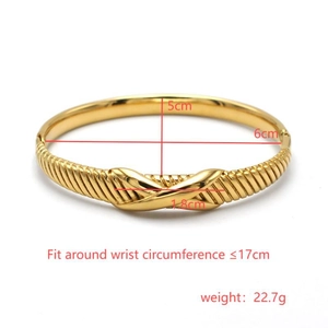 Detail van vergulde titanium armband met kruisvormige knoop en diagonale gegraveerde textuur