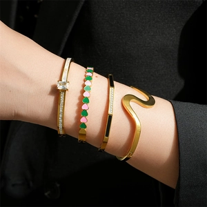 Détail de bracelets dorés empilés avec émail en cœur et détails en zircon