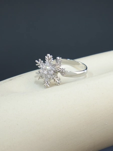 Gros plan sur une bague flocon de neige argentée ornée de zircons brillants sur fond bleu