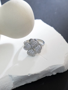 Macro shot of silver four-leaf clover ring with sparkling zircon inlays on stone base