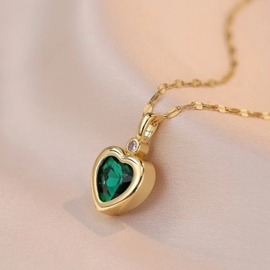 Elegant gold necklace featuring a dark green heart-shaped gemstone pendant with a small diamond