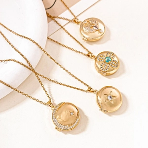 Detail of four golden round locket necklaces with zircon patterns on stone background