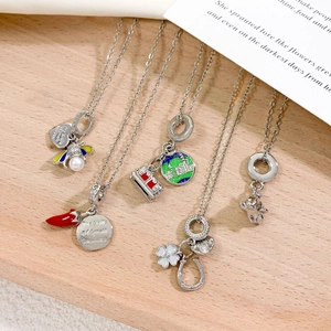 Five unique titanium steel pendant necklaces with bee, chili, and koala designs on wood
