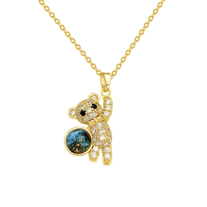 Golden bear pendant necklace with white crystals and blue starry globe on white background
