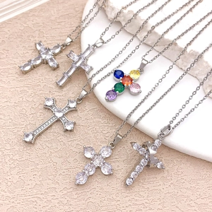Silver cross necklaces with cubic zirconia pendants on a stone display stand