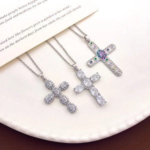 Tres collares de cruz con circonitas y gemas de colores sobre un plato blanco