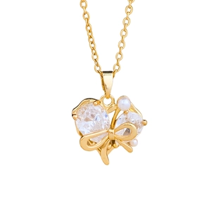 Elegante collar de corazón con lazo dorado de circonita y perla sobre fondo blanco