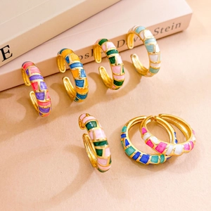 Adjustable gold plated enamel ring featuring a colorful geometric mosaic pattern on a desk